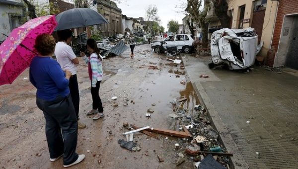 People look on as debris is seen along a street in Dolores, the day after the city was hit by a tornado.