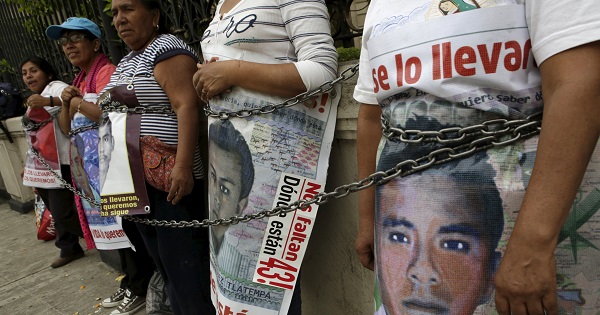Relatives hold pictures of the 43 Ayotzinapa students as they chain themselves to a fence during a protest outside the Interior Ministry in Mexico City, April 15, 2016.