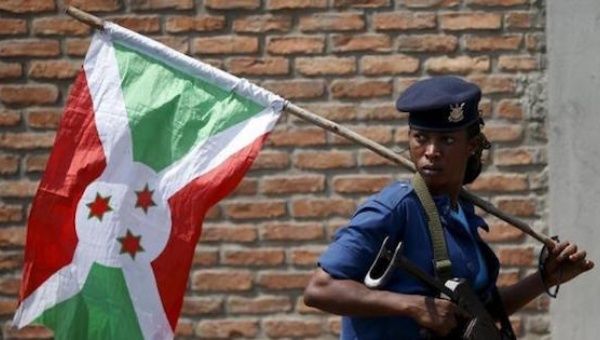 A policewoman carries a Burundi flag during a protest against President Pierre Nkurunziza's decision to run for a third term in Bujumbura, Burundi, May 29, 2015.