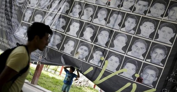 A child stands underneath a banner showing the photographs of the 43 missing students of the Ayotzinapa teachers' training college.