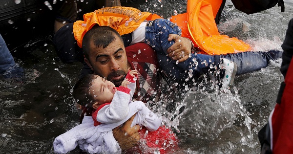 A Syrian man holds onto his children as he struggles the Greek island of Lesbos, after crossing a part of the Aegean Sea from Turkey to Lesbos Sept. 24, 2015.