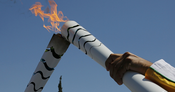Olympic flame second torch bearer, former volleyball player Giovane Gavio from Brazil (L), passes the torch to third bearer Dimitrios Mougios as they attend the Olympic flame lighting ceremony for the Rio 2016 Olympic Games on the site of ancient Olympia, Greece, April 21, 2016.
