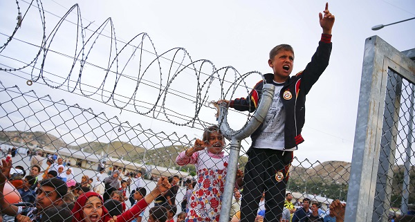 Refugee youths gesture from behind a fence as officals arrive at Nizip refugee camp near Gaziantep.
