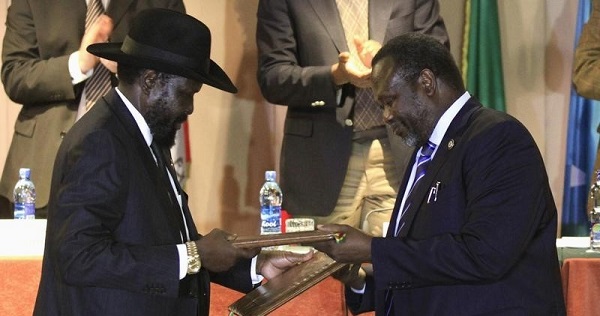 South Sudan's President Salva Kiir (L) and South Sudan's rebel commander Riek Machar exchange documents after signing a ceasefire agreement during the Inter Governmental Authority on Development (IGAD) Summit.