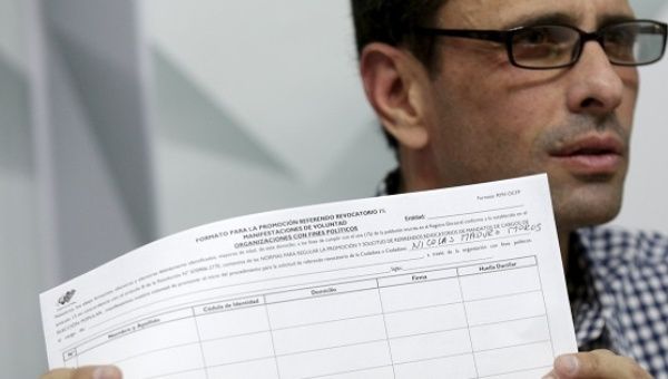 Opposition leader Henrique Capriles shows a copy of the form to collect signatures to initiate a recall referendum to remove President Maduro, Caracas, April 26, 2016. 