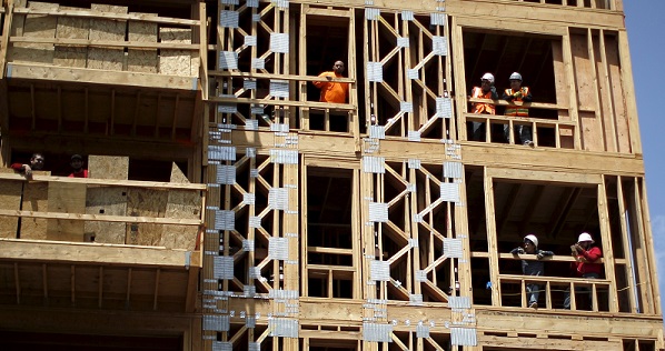 Construction workers look out of the windows of a new residential building in downtown Los Angeles, California.
