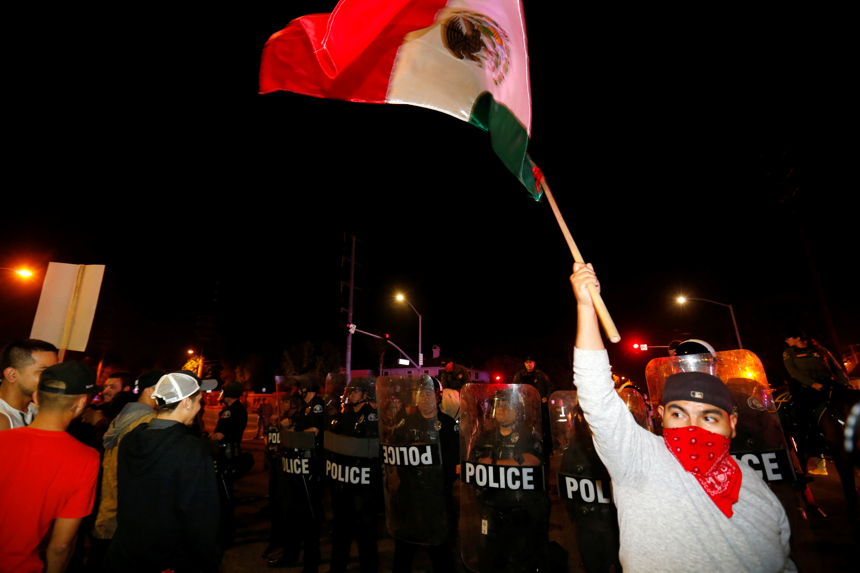 Police in riot gear form a line to begin to break up a group of protesters, one with a Mexican flag, outside Republican U.S. presidential candidate Donald Trump's campaign rally in Costa Mesa, California, April 28, 2016.
