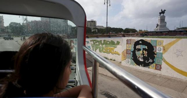 A tourist from Peru looks at a graffiti of revolutionary hero Ernesto ''Che'' Guevara from the top of a double decker sightseeing bus in Havana in this Jan.17, 2016
