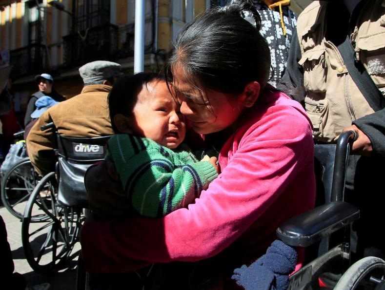 A woman with a physical disability and a child cry during a rally during a rally demanding the government to increase their monthly disability subsidy.