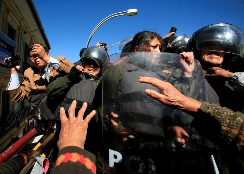 Riot police officers try to stop demonstrators with physical disabilities during a rally.