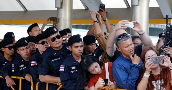 Thai police and people look at student activist Sirawith Seritiwat, an anti-coup activist, as he is detained by the police while demonstrating alone against a military-backed draft constitution in Bangkok