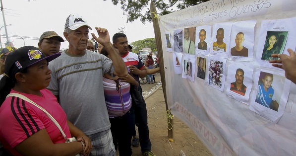 People look at displayed pictures of missing miners in Tumeremo in Bolivar, Venezuela.