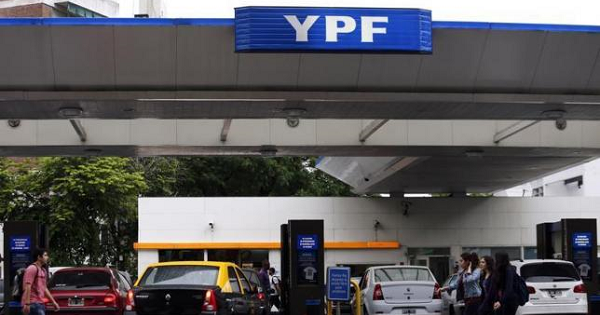 People walk past a YPF petrol station in Buenos Aires Nov. 26, 2013.