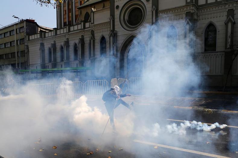 A student protester kicks a tear gas canister during a demonstration to demand changes in the education system in Santiago.