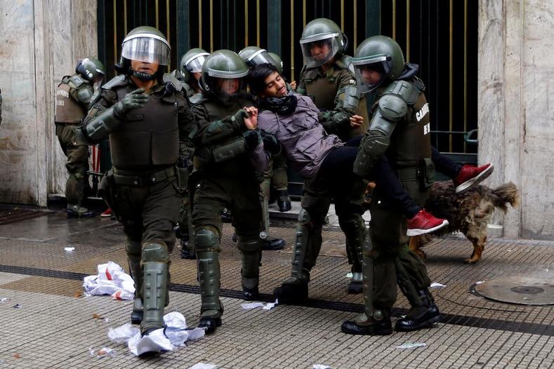 A student protester is detained outside the education ministry building during a rally to demand changes in the education system in Santiago. 