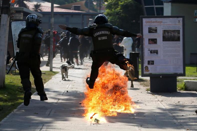 A riot policeman jumps over a molotov bomb during clashes with student protesters during a demonstration to demand changes in the education system in Santiago. 