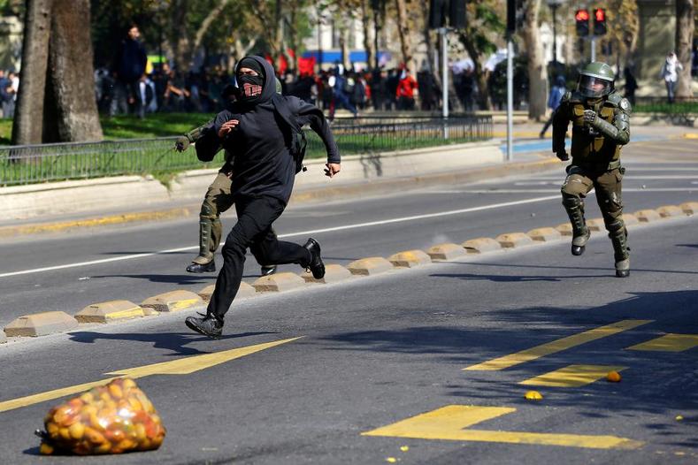 A student protester runs away from riot policemen during a demonstration to demand changes in the education system in Santiago. 