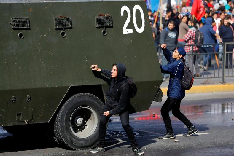 Student protesters hit a riot police vehicle during a demonstration to demand changes in the education system in Santiago. 