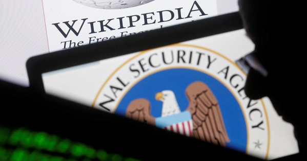 A man is seen near cyber code and the U.S. National Security Agency logo in this photo illustration taken in Sarajevo March 11, 2015