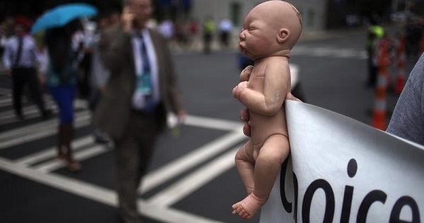 A pro-life activist holds a doll and banner while advocating his stance on abortion near the site of the Democratic National Convention in Charlotte, North Carolina.