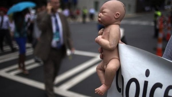 A pro-life activist holds a doll and banner while advocating his stance on abortion near the site of the Democratic National Convention in Charlotte, North Carolina.
