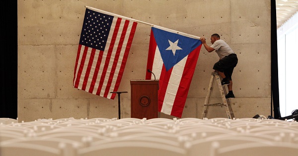 A worker takes off the U.S and Puerto Rican flag after a rally of U.S. Democratic presidential candidate Bernie Sanders in San Juan.