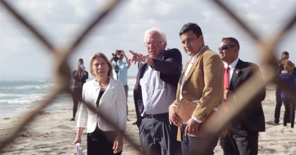 Bernie Sanders points to the border fence during a visit to the U.S.-Mexican border alongside Maria Puga (L) and Christian Ramirez (R), May 21, 2016.