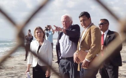 Bernie Sanders points to the border fence during a visit to the U.S.-Mexican border alongside Maria Puga (L) and Christian Ramirez (R), May 21, 2016.