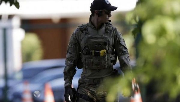 A federal police officer walks in front of the home of former house speaker Eduardo Cunha during a raid in Brasilia, Brazil, Dec. 15, 2015.