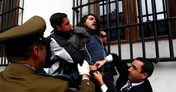 Police guards attempt to detain a chained demonstrator during a protest inside the government house against the government's education reform in Santiago, Chile, May 24, 2016.