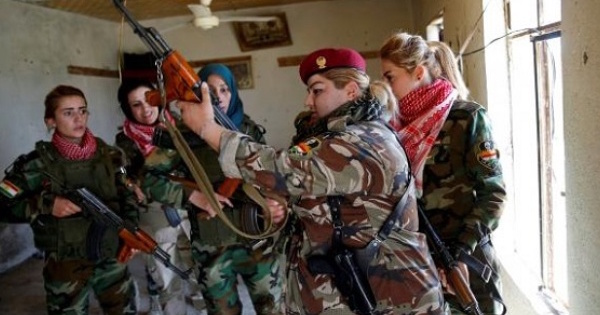 Iraqi Kurdish female fighter Haseba Nauzad (2nd R), 24, holds her weapon as she is surrounded by comrades at a site during a deployment in Nawaran near Mosul, Iraq.