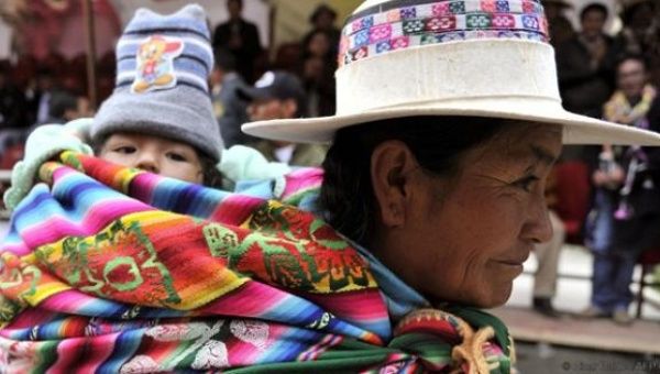 An Aymara woman carries her baby.