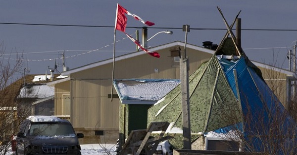 A tattered Canadian flag flies over a teepee in Attawapiskat, Ontario.