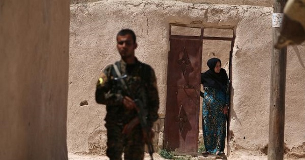 A Syria Democratic Forces fighter stands near a woman in a village, on the outskirts of Manbij city, after they ousted Islamic State group forces, Syria June 8, 2016.