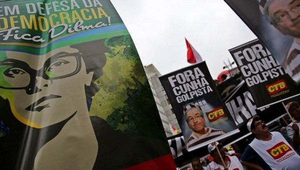 Protesters carry signs in favor of Dilma Rousseff and against Eduardo Cunha during a protest against the impeachment process in Sao Paulo, Dec. 16, 2015.