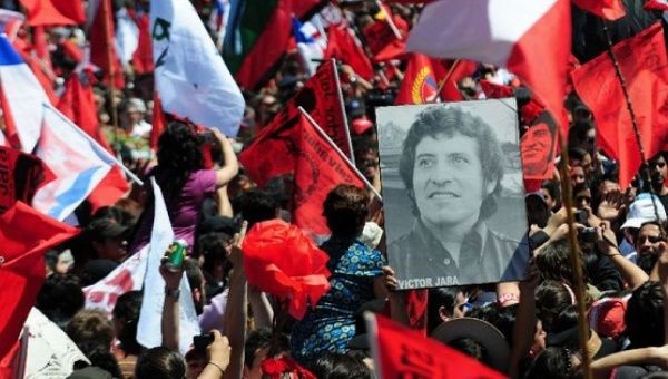 People hold the portrait of Chilean singer Victor Jara, during a funeral ceremony in Santiago, Dec. 5, 2009.