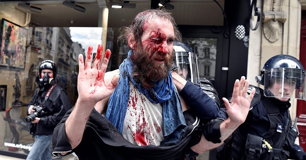 An injured protester is led away by riot police in Paris on Tuesday.