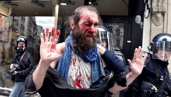 An injured protester is led away by riot police in Paris on Tuesday.