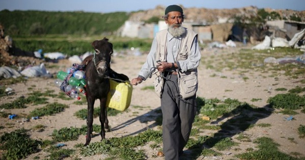 A Palestinian man pulls his donkey loaded with empty bottles and a jerrycan, as he makes his way to fill them with drinking water.