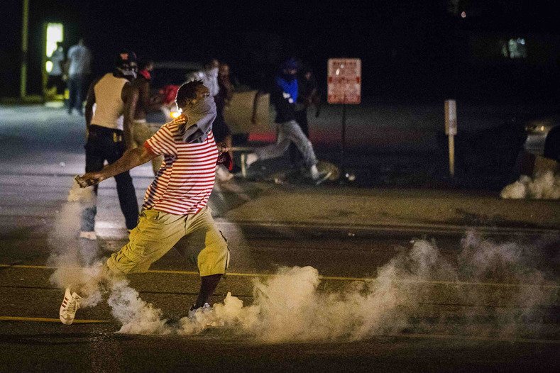 The #BlackLivesMatter movement has become a major player in U.S. politics and is seen as a continuation of the Black Power legacy's demands for dignified treatment, living conditions, and an end to police abuse and impunity. A protester picks up a tear gas canister to throw back towards police as demonstrations continue over the shooting of Michael Brown in Ferguson, Missouri on August 17, 2014.