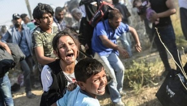 Syrian children fleeing the war cry after passing through broken down border fences to enter Turkey.