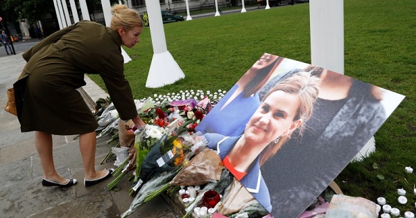 In the picture, a woman leaves flowers beside a photograph of the murdered Labour MP Jo Cox in Parliament Square, London, UK.