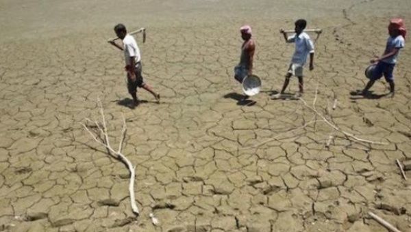 Laborers walk through a parched land of a dried lake on the outskirts of Agartala, capital of India's northeastern state of Tripura.