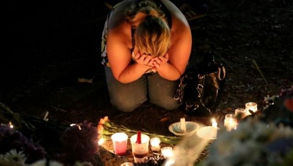 A woman mourns as she sits on the ground and takes part in a vigil for the Pulse night club victims following last week's shooting in Orlando, Florida.