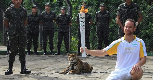 Brazilian physiotherapist Igor Simoes Andrade poses for picture next to jaguar Juma as he takes part in the Olympic Flame torch relay in Manaus, Brazil, June 20, 2016.