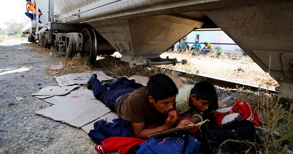 Central American migrants rest next to the train tracks while waiting for the freight train 
