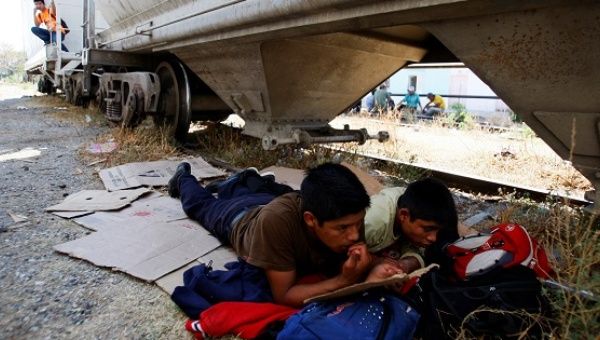 Central American migrants rest next to the train tracks while waiting for the freight train 