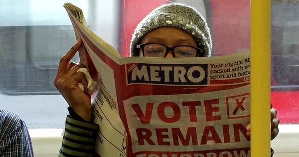 A woman reads a newspaper on the underground in London with a 