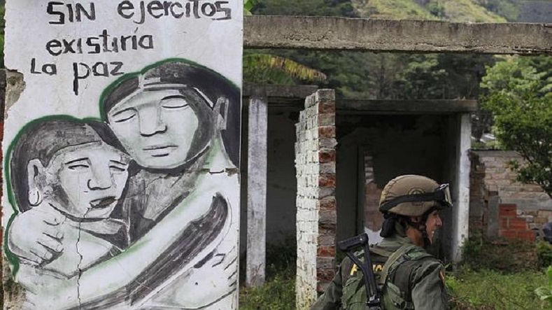 A Colombian police officer walks by a mural that reads 
