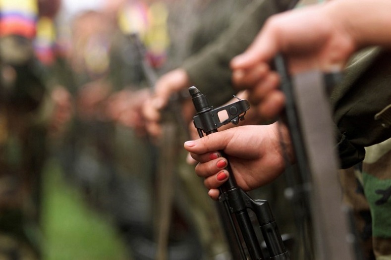 A Colombian fighter grips her weapon while participating in a FARC ceremony in Villa Colombia camp near San Vicente del Caguan, Colombia, April 29, 2000. The Government of Colombia and FARC signed a landmark agreement Thursday to declare a definitive bilateral ceasefire, a covenant that marks the end of the oldest armed conflict in the hemisphere.